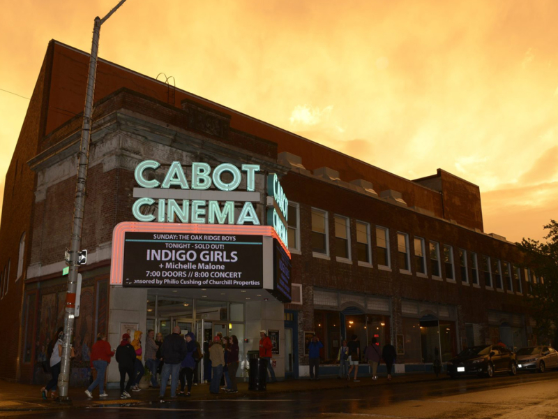 The outside of The Cabot during sunset, the words Cabot Cinema are lit up on a neon sign.