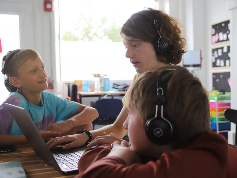 A woman with two young people looking at a laptop